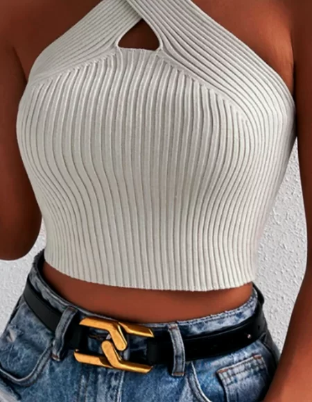 A stylish woman in a white crop top and jeans, looking confident and trendy.